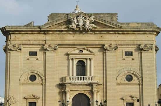 Detalle superior de la fachada con escultura y frontón triangular