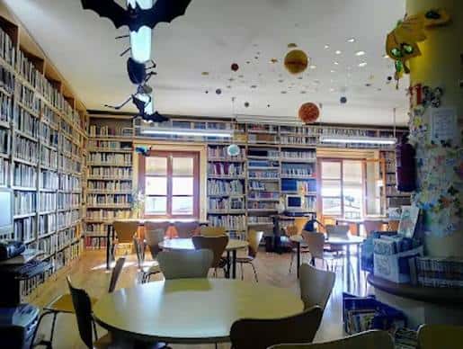 Interior infantil de la biblioteca con estanterías, mesas y decoración temática
