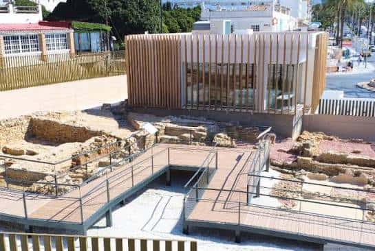 Vista exterior del Centro de la Historia de Benalmádena con ruinas arqueológicas y pasarela de madera