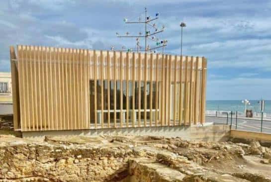 Fachada moderna del Centro de la Historia junto al mar, con estructuras históricas en primer plano