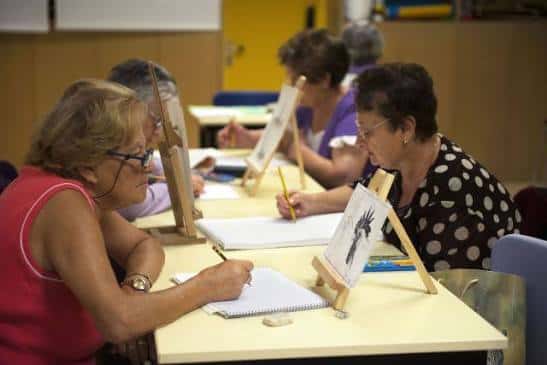 Taller de dibujo al natural con caballetes y participantes concentrados