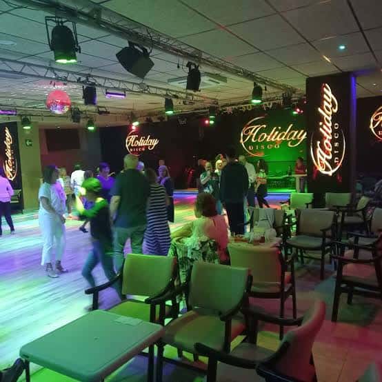 Interior de la discoteca Holiday con pista de baile y luces de colores