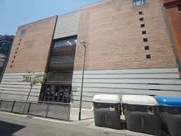 Vista exterior del Centre Cívic Fondo con fachada de ladrillo y contenedores en primer plano