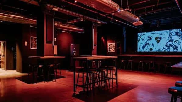 Interior del bar con iluminación roja y pantalla de proyección