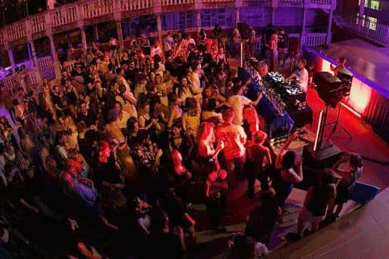 Evento musical en el patio exterior con público y DJ