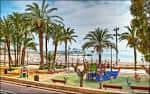 Vista del Parque de Elche con palmeras y zona de juegos infantiles junto al mar