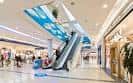 Interior del centro comercial con escaleras mecánicas y tiendas
