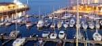Marina de Vigo con yates y edificios iluminados al atardecer