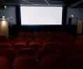 Interior de una sala de cine con butacas rojas y pantalla grande