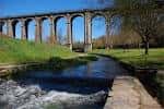 Viaducto de A Chanca con un arroyo en primer plano y entorno natural.