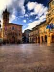 Vista panorámica de la Plaza de la Constitución, mostrando la Iglesia de San Isidoro y el Ayuntamiento bajo un cielo dramático