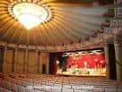 Interior del auditorio con butacas y escenario iluminado por una lámpara central