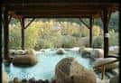 Detalle de una piscina termal con rocas bajo una estructura de madera