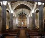Interior de la nave central de la iglesia con el retablo mayor iluminado.