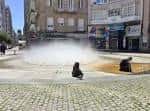 Fuente de los Niños con efecto de niebla de agua y edificios urbanos al fondo