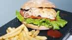 Hamburguesa con patatas fritas y salsa en un plato oscuro