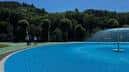 Piscina exterior con fuente y zona verde en el Complejo de Oira
