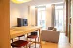 Zona de comedor con barra y sala de estar iluminada por ventanales en apartamento boutique