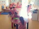Aula de escuela infantil con niños jugando en mesas y alfombras de colores