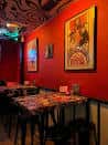 Zona de mesas y sillas con paredes rojas y cuadros en el restaurante Ummagumma