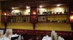 Zona de comedor de un restaurante con estanterías decoradas y mesas puestas en Vigo