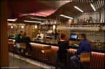 Zona de barra del restaurante con iluminación ambiental y clientes