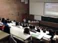 Interior de un aula magna o auditorio con asientos y pantalla de proyección