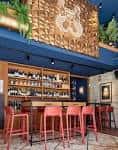 Barra de bar elegante con estanterías de botellas y taburetes altos