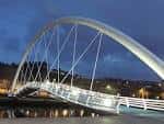 Puente moderno iluminado sobre el río Lérez al anochecer