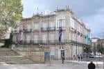Exterior del edificio con banderas en la fachada y plaza