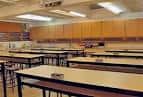 Aula o sala de usos múltiples con mesas largas y mobiliario de almacenamiento