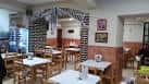 Interior del restaurante con mesas y sillas de madera, mostrando el ambiente tradicional