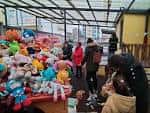 Mercado de Navidad al aire libre con puestos de juguetes y visitantes.