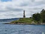 Faro de la Illa de Tambo emergiendo entre la vegetación junto al mar