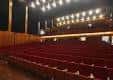 Interior del auditorio con butacas rojas y escenario vacío
