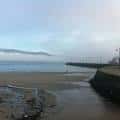 Playa y muelle de la ETEA en un día nublado, con el mar y la costa de Vigo.