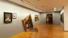 Sala de exposición de arte con obras y suelo de madera