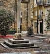 Crucero de piedra en la Praza de San Martiño con edificios históricos al fondo