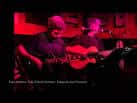Músicos actuando en el escenario del Café Cultural Auriense bajo iluminación roja