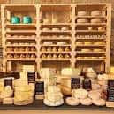 Exposición de quesos variados en estanterías de madera y mostrador
