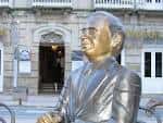 Estatua de Paz Andrade en la Praza de San Xosé con un edificio clásico de fondo