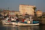 Barcos de pesca tradicionales amarrados en el muelle de Curuxeiras con edificios históricos al fondo