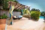 Área de descanso exterior con pérgola y mobiliario lounge junto a la piscina