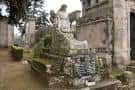 Tumba antigua cubierta de musgo con una estatua de ángel