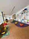 Interior de la ludoteca con zona de juegos y estanterías