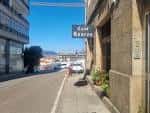 Vista de la calle con el letrero de Casa Roucos en Vigo y el puerto al fondo