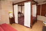 Habitación de hotel con cama con dosel y cortinas blancas