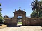 Entrada principal de piedra del Cementerio de San Amaro con palmeras