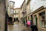 Calle Rúa do Vilar con edificios de piedra, tiendas y personas caminando.