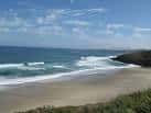 Olas rompiendo en la orilla de la Playa de Barrañán con acantilados